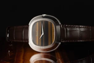 Piaget Andy Warhol watch with tiger's eye dial lying on the side on a wooden surface.