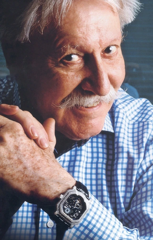 Portrait of Gérald Genta smiling while wearing a Gerald Charles watch, highlighting his influence on Swiss luxury design.