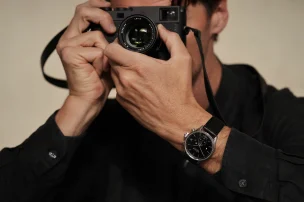 Die Leica Camera ZM 2 Uhr mit Handaufzug am Handgelenk zusammen mit einer Kamera, dritte Ansicht.