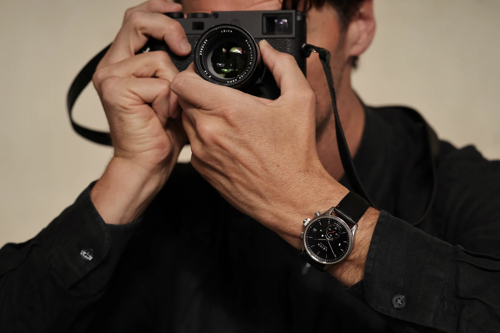 Die Leica Camera ZM 2 Uhr mit Handaufzug am Handgelenk zusammen mit einer Kamera, dritte Ansicht.