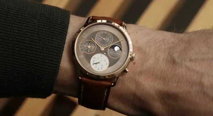 Hermès Slim d’Hermès Perpetual Calendar in Roségold am Handgelenk mit braunem Lederband und ewigen Kalenderanzeigen.