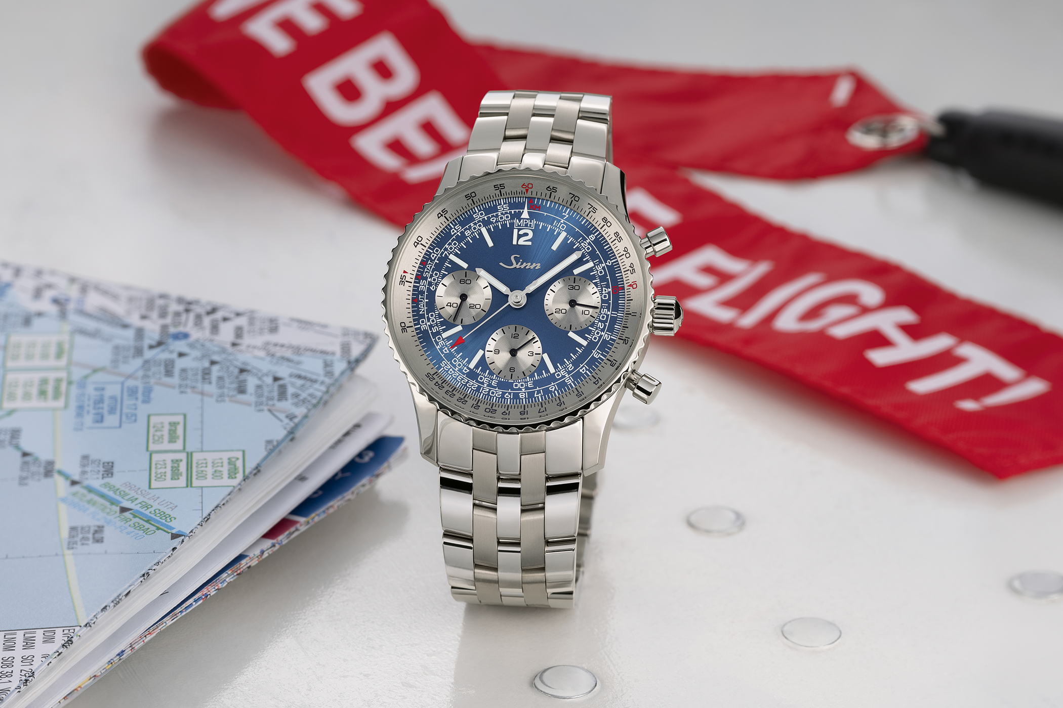 Die Sinn 903 Ti II Jubiläum Chronograph mit blauem Zifferblatt, silbernen Totalisatoren, Tachymeter- und Rechenschieber-Skala sowie mehrgliedrigem Edelstahlarmband, frontal aufgenommen.